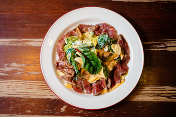 Beef tataki with banana salad. Pan-Asian oriental cuisine on wooden table.