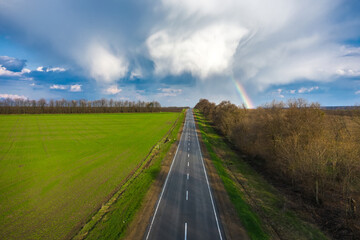 Fototapeta na wymiar Rainbow over rural highway road spring landscape aerial view