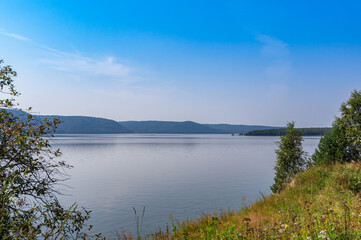 Summer landscape with water, greenery, forest and mountains. View of the Angara River on a sunny summer day. Taltsy village, Irkutsk region, Russia