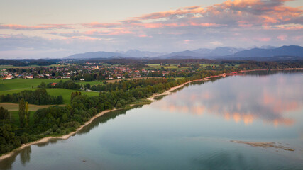 Fototapeta na wymiar Lake Chiemsee in Bavaria with the Alp mountains during sunset from above, with village Chieming, during summer.