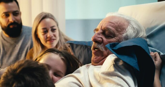 Aged male patient hugging grandchildren near parents