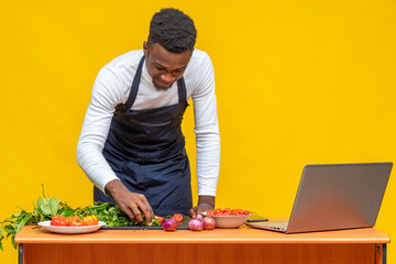 young black chef preparing a meal with a laptop on his table