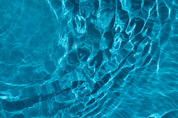 Sun glare in the transparent blue water.  Blue water wave texture background.