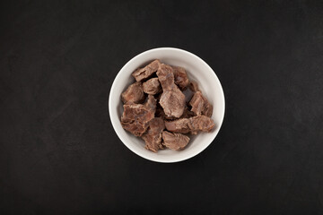 Pieces of beef or lamb in white bowl, top view. Dietary boiled meat. Dark background, space for text