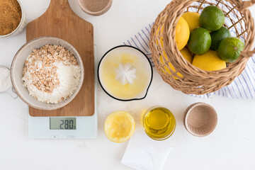 Some mixed muffin components over a digital kitchen scale next to a juicer full of lemon juice and more vegan fresh ingredients.
