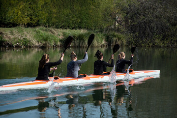 Portrait on back view of four women  rowing in the channel in kayak
