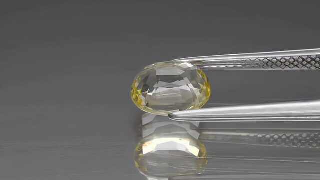 natural heliodor yellow beryl gemstone in the tweezer on the turn table