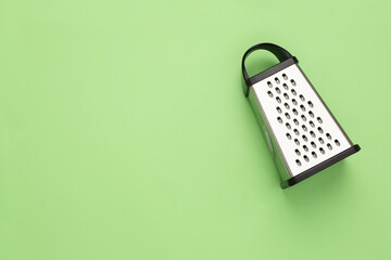 Fototapeta na wymiar Stainless steel grater isolated. Kitchen accessories. Tools for cooking. Isolated on green background. Flat lay.