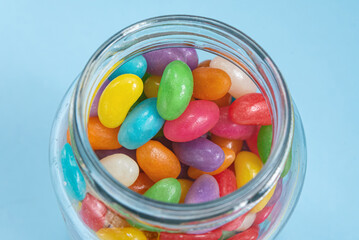 Several Jelly Beans on the blue background inside the glass pot