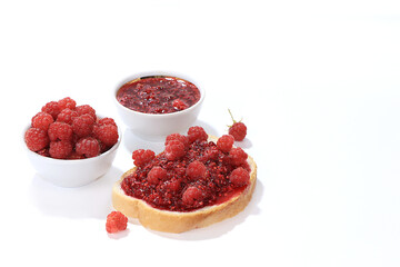 Fresh red raspberries in a cup and bruschetta with jam and fresh raspberries on white isolated background, selective focus, Natural summer berry, healthy food concept. Delicious breakfast, 