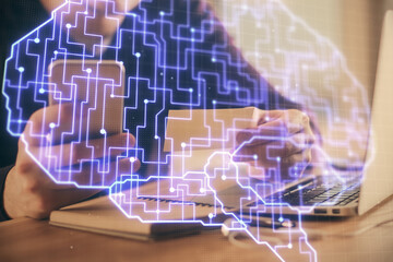 Double exposure of man's hand holding and using a digital device and brain hologram drawing. Data...