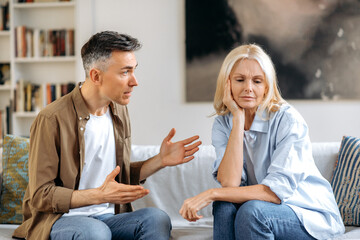 Emotional dialogue of a married couple in the living room on the couch. Outraged worried husband...