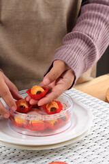 Asian Female Hand Put  Kue Kering (Cookies) on the Clear Box, Preparation for Sale Ied Mubarak Kue Lebaran. Arrange Ied Cookie on the Box. Mengatur Kue Lebaran di Toples