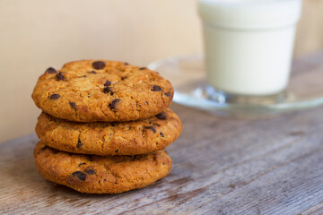 Homemade cookies with chocolate drops and salt  with close up on the wooden table. Tree tasty biscuits with glass of cold milk as a snack for kids. Sweet and simple dessert as a breakfast idea.