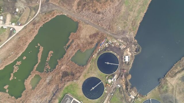 Waste water treatment plant. Top down shot. Sewage separation tanks - circular and rectangular. Lake nearby.