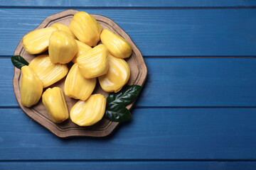 Delicious exotic jackfruit bulbs on blue wooden table, top view. Space for text