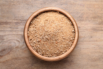 Fresh breadcrumbs in bowl on wooden table, top view