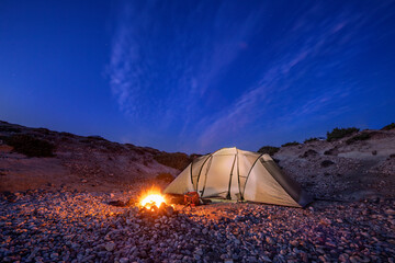 Fototapeta na wymiar campers tent in the night with mountains and dark blue sky 