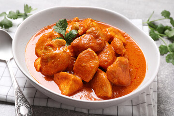 Bowl of delicious chicken curry on light grey table, closeup
