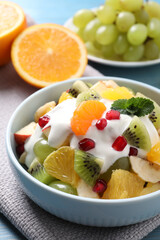 Delicious fruit salad with yogurt on table, closeup