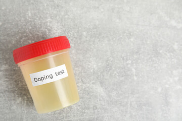 Jar of urine with words Doping test on light grey stone table, top view. Space for text