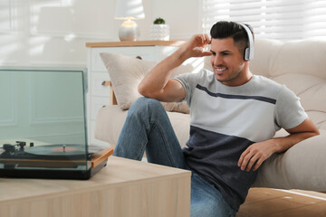 Fototapeta premium Happy man listening to music with turntable at home