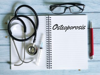 Medical concept. Phrase osteoporosis written on notebook with a pen,eye glasses,syringe and...