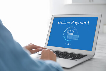 Woman using laptop for online payment at table, closeup