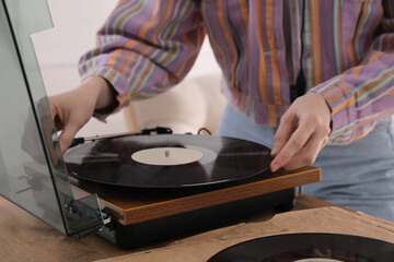 Young woman using turntable at home, closeup