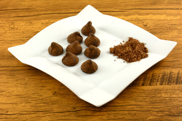 Cocoa dusted chocolate truffles with cocoa powder on white snack plate on table