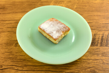 Custard cream cortadillo cake on green dessert plate on table