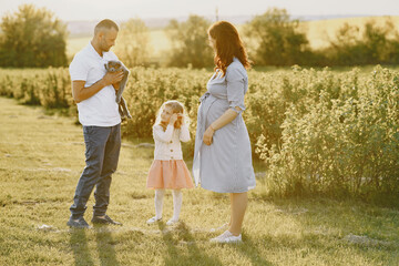 Family with little daughter spending time together in sunny field