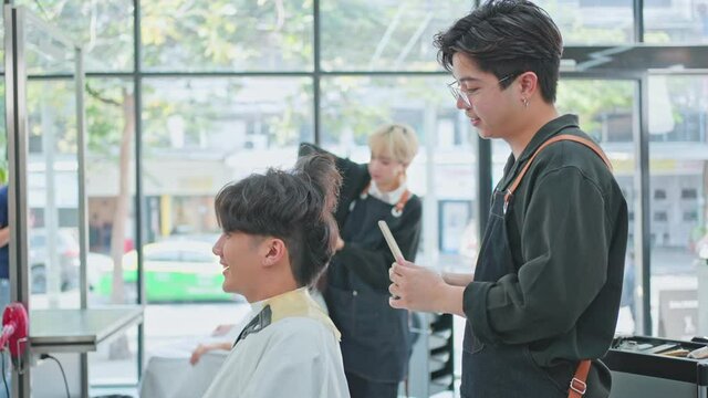 Male and female hairdressers cutting customer's hair in beauty salon.