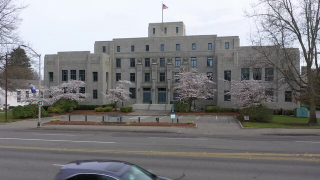 Cinematic rise and reveal aerial drone footage of the springtime cherry blossoms at the Washington State Capitol Building and Campus, Capitol Court Building in Olympia, Washington