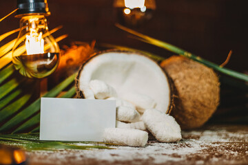 Concept of coconut candy with a ripe half cut coconut with green leaves on a brick wall background