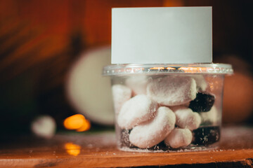 Concept of coconut candy with a ripe half cut coconut with green leaves on a brick wall background