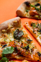 Beautiful appetizing shot of slices of smoked salmon pizza placed in a row, close up on orange background
