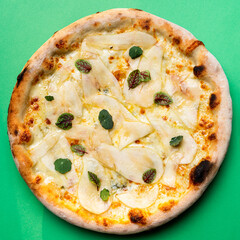 Top view of a whole pear and cheese pizza on bright background