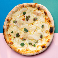 Top view of a whole pear and cheese pizza on bright background
