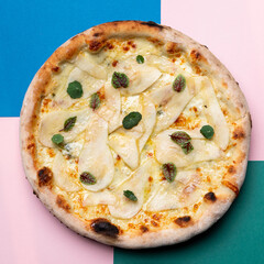 Top view of a whole pear and cheese pizza on bright background
