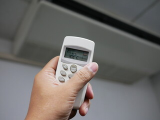 closeup of hand using remote control air conditioner in office.
