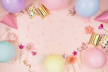 Background for happy birthday celebration or party. Group of colored balloons , confetti, candles, ribbons on pastel pink background.  Mock up with copy space, place for text