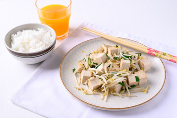 Stir fried tofu with mung bean sprouts eating with cooked rice and orange juice on white background, Asian healthy vegan food