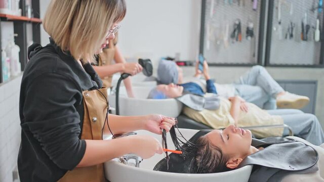 Asian young girl getting hair treatment by professional hairdresser.