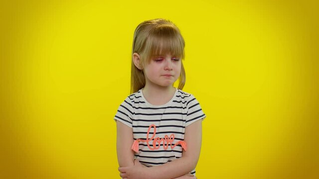 Upset disappointed little blonde teen kid child girl with tears on eyes cries from despair, being sad because of unfair things. Isolated on yellow studio background. Young children lifestyle emotions