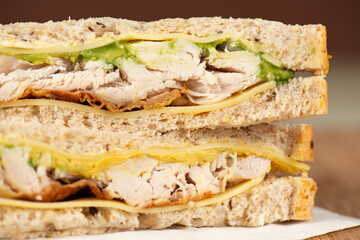 Detailed closeup of shredded roast chicken, sliced cheese and avocado on multigrain bread.