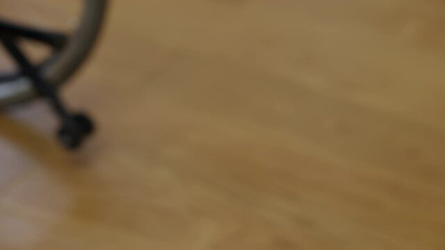 Young female hand rolling wheelchair wheel indoors. Close-up of unrecognizable disabled Caucasian woman leaving. Paralysis and disability concept
