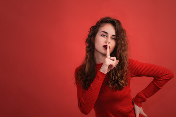 The girl poses in the studio and holds her finger to her mouth. A young woman of 20 years old in a...