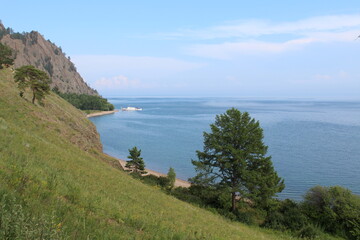 Fototapeta na wymiar White boat ship sails on Lake Baikal, surrounded by coniferous forest in the summer