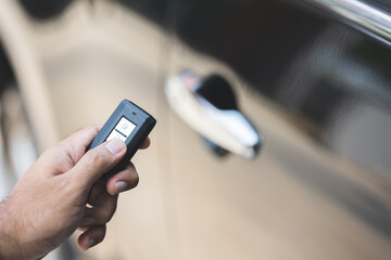 Close up male hand holding car key. Man unlock car door by remote key push button near car door.